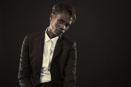 Portrait of confident businesswoman sitting against black backgroundの写真素材