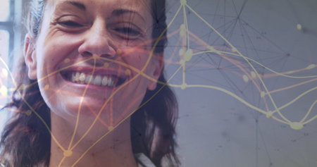 Smiling mid-adult woman wearing white collared top showing network overlay in office, copy space. Professional, technology, futuristic, innovation, communication, digital, corporateの写真素材