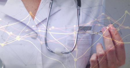 Holding badge, doctor displaying network overlay on white lab coat in clinic with stethoscope. Medical, healthcare, innovation, technology, professional, diagnostics, digitalの写真素材