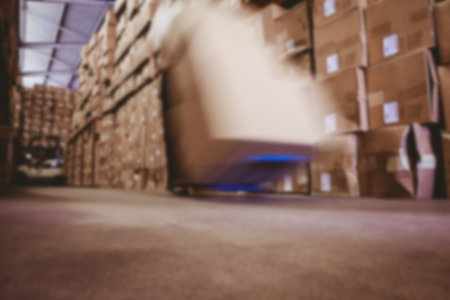 Blurred view of cardboard boxes on handtruck in warehouseの写真素材
