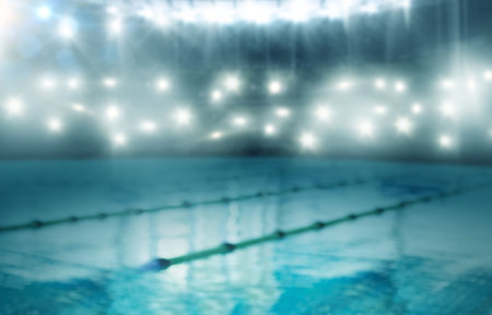 Flat design competitive pool is glowing under bright floodlights with diagonal lane dividers. Sports, aquatic, minimalist, night, ambiance, reflection, competitionの写真素材