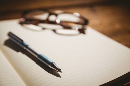 Close-up of eyeglasses and pen on bookの写真素材