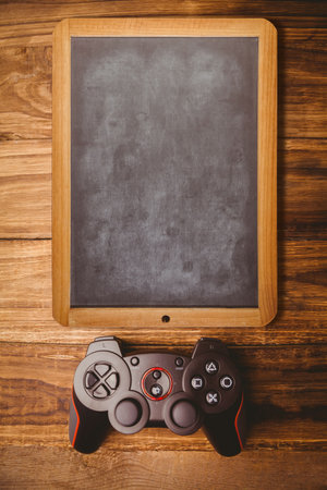 Flat vector showing blank wooden framed chalkboard on tabletop with black red game controller. Interactive, education, entertainment, modern, rustic, gadget, gamingの写真素材