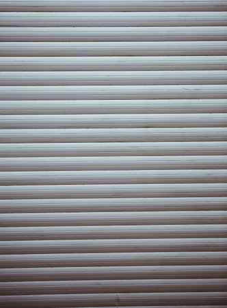 Metal roller shutter is being shown in flat design, showing grey hues and horizontal slat texture....