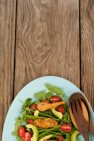 Overhead view of fresh salad in blue plate on brown wooden tableの写真素材