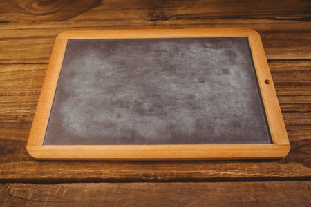 Blank rectangular chalkboard with wooden frame is lying flat on rustic wood table in flat design....