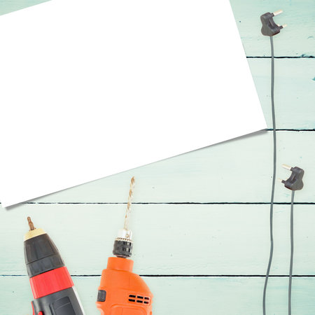 Close-up drill machines with plugs and paper on wooden surfaceの写真素材