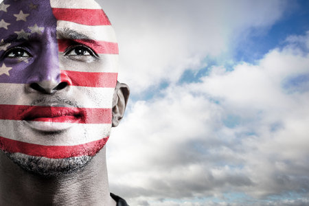 Man is gazing upward in vector portrait, featuring flag face paint beneath cloudy sky. Patriotism, celebration, expression, symbolic, outdoor, vibrant, unityの写真素材