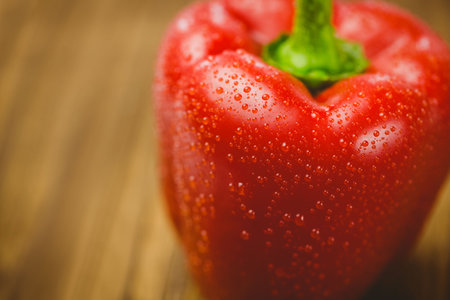 Close-up of fresh red pepper with water drops on wooden tableの写真素材