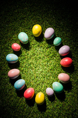 Overhead view of various colorful Easter eggs in circle on grass at garden