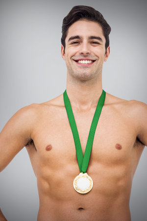 Portrait of shirtless male athlete with medals against gray backgroundの写真素材