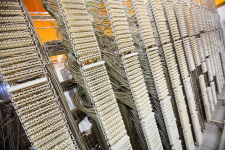 Showing close-up telecom frame with white punch-down blocks and grey cables on orange wall....