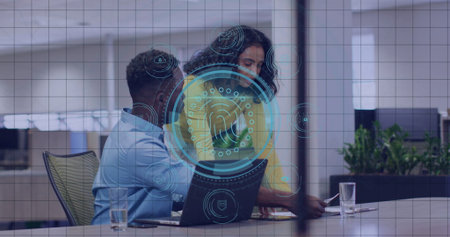 Leaning woman pointing and man examining biometric overlay on laptop at conference table in office....
