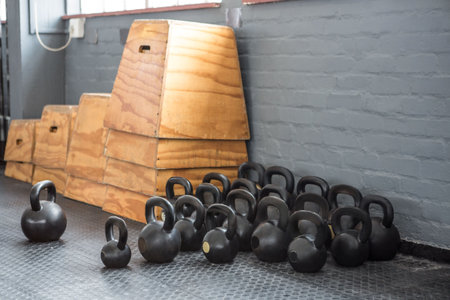 Group of kettlebells is filling flat design gym corner with rubber mat, showing stacked plyo boxes. Fitness, strength, training, workout, equipment, industrial, minimalistの写真素材