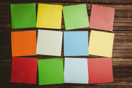 Directly above shot of various square shaped colorful papers on wooden floorの写真素材