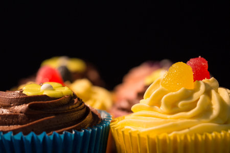 Flat illustration is featuring cupcakes in colorful liners with buttercream swirls and gumdrops. Desserts, confections, patisserie, gourmet, bakedgoods, celebration, eleganceの写真素材