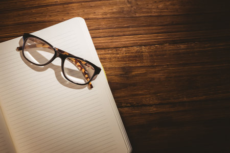 Eye glasses on blank book over wooden tableの写真素材