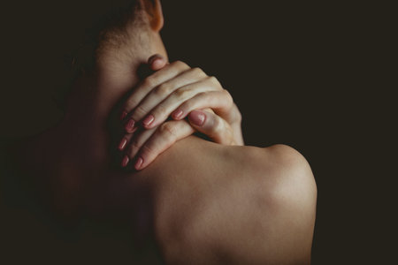 Showing woman raising hands on nape in flat illustration with manicured nails and low-key lighting. Minimalist, elegance, femininity, beauty, serenity, sophistication, portraitの写真素材