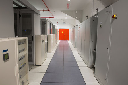 Showing flat design electrical corridor with raised floor tiles, cabinets, red piping and exit door....