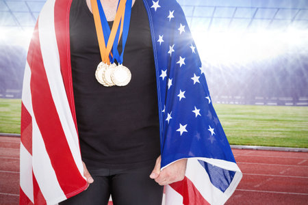 Midsection of male athlete with American Flag and medals at stadiumの写真素材