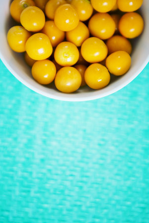 Overhead view of raw cherry tomatoes in bowl on tableの写真素材