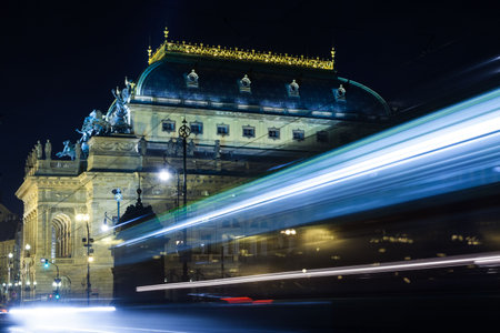Historic classical building is glowing under warm lights in flat design, with tram light trails. Heritage, urban, illumination, transportation, architecture, nightscape, vintageの写真素材