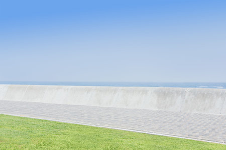 Promenade by sea against clear blue sky during sunny dayの写真素材