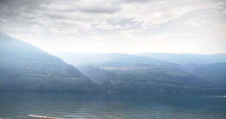 Scenic view of river by mountain against sky during foggy weaher