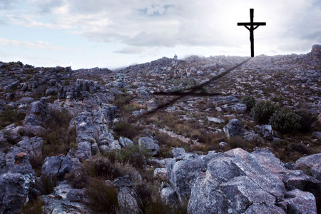 Rugged rocky hillside is showing in flat design with solitary cross casting shadow under cloudy sky. Mountainous, landscape, minimalist, spiritual, outdoor, serene, natureの写真素材