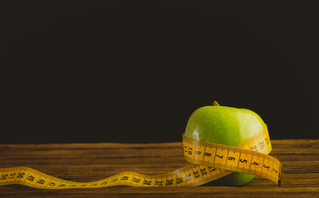 Green apple and measuring tape on wooden table