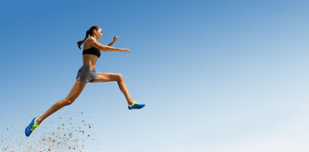 Low angle view of female athlete long jumping against blue sky