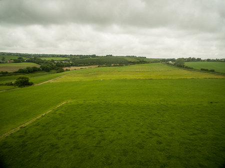 Aerial view of green landscape against cloudy skyの写真素材
