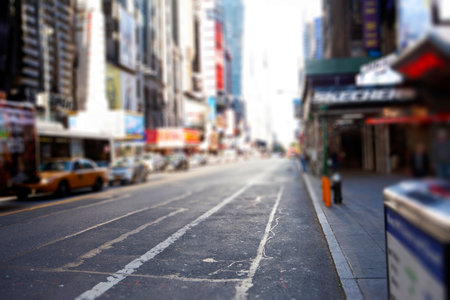 Sunny city street is being illustrated in flat design, with parked yellow taxis and blurred figure. Urban, commercial, vibrant, transportation, cityscape, pedestrian, infrastructureの写真素材