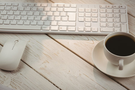 High angle view of keyboard and mouse with coffee cup on table