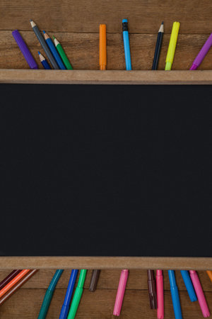 High angle view of blank chalkboard with colorful equipment on wooden tableの写真素材