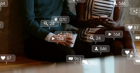 Sitting friends holding smartphone and coffee cup in cafe, floating social notification icons....