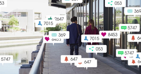 Walking two colleagues wearing blazer, carrying bag along canal walkway, showing social media icons. Urban, contemporary, professional, networking, connection, technology, reflectionの写真素材