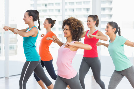 Five women performing synchronized lunge exercise in flat design fitness studio with city view. Athletes, teamwork, vitality, modern, empowerment, wellness, choreographyの写真素材