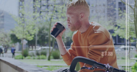 Cyclist wearing orange sweatshirt sipping from black coffee cup in park plaza, with bicycle, ledge....