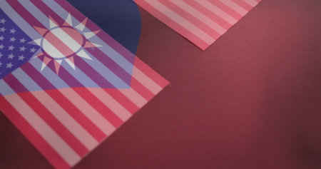 Displaying overlapping paper flags on deep red mat surface, with United States and Taiwan motifs. Diplomacy, cooperation, international relations, symbolism, flat lay, minimalistic, professionalの写真素材