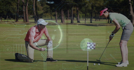 Kneeling man marking golf ball and woman lining up putt on putting green, wearing polo shirts. Athletics, outdoor, leisure, teamwork, sport, casual, vibrantの写真素材