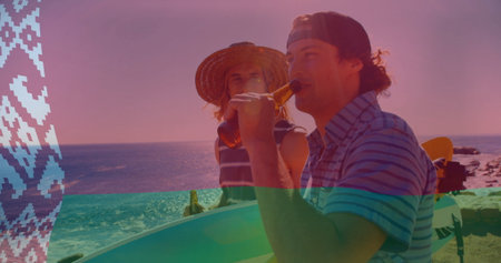 Standing two men in beachwear holding surfboards and sipping amber beer bottles on rocky beach....