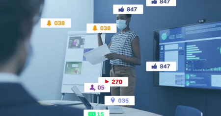 Presenting Black woman in mask holding charts at flipchart in meeting room, with notification icons....