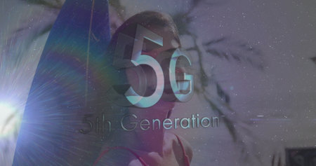 Standing woman facing ocean on sandy beach, presenting 3D 5G text with surfboard and lens flare. Technology, connectivity, innovation, outdoor, minimalist, futuristic, communicationの写真素材
