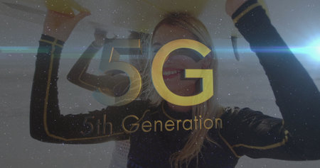 Smiling woman in black gold top holding panel overhead in studio, with 5G 5th Generation display....