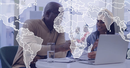Discussing documents man in zip-collar sweater and woman in headscarf in office, with map overlay....