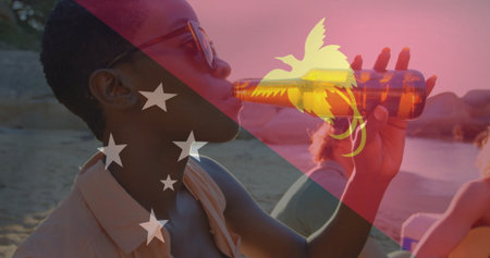 Woman wearing sunglasses sipping from brown bottle on beach with flag overlay, copy space. Relaxation, leisure, vacation, outdoor, friendship, serenity, lifestyleの写真素材