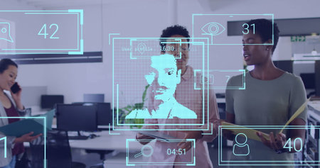 Collaborating women in blouses viewing facial recognition overlay in office, with smartphones. Technology, teamwork, innovation, digital, professional, modern, dataの写真素材