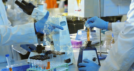 Scientist in white coat dispensing amber solution into test tube at lab bench, with vortex mixer....