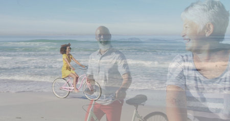 Three-generation family cycling and standing on beach, smiling with pink cruiser and black bicycles. Family, vacation, leisure, tranquility, summer, harmony, nostalgiaの写真素材